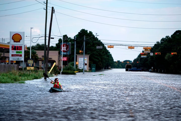 A woman paddles down a flooded road while shuttling deliveries for her neighbors during the aftermath of Hurricane Harvey on