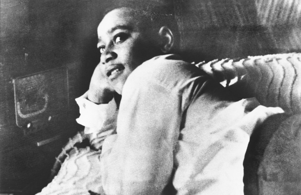 Emmett Till is photographed lying on his bed. 