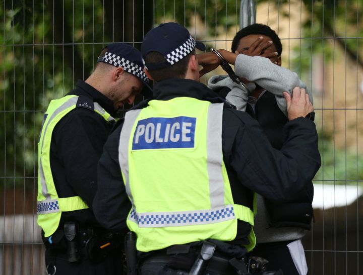 Police officers handcuff a man at Notting Hill Carnival in west London