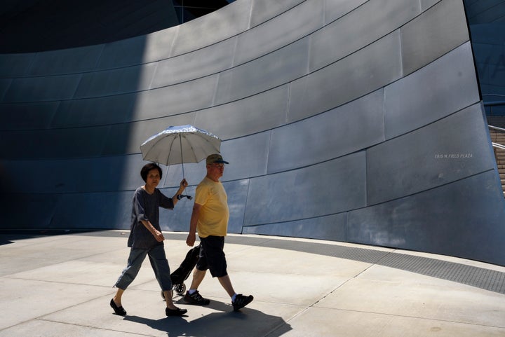 Pedestrians outside the Walt Disney Concert Hall in Los Angeles on Aug. 7 shield themselves from the sun as the temperat