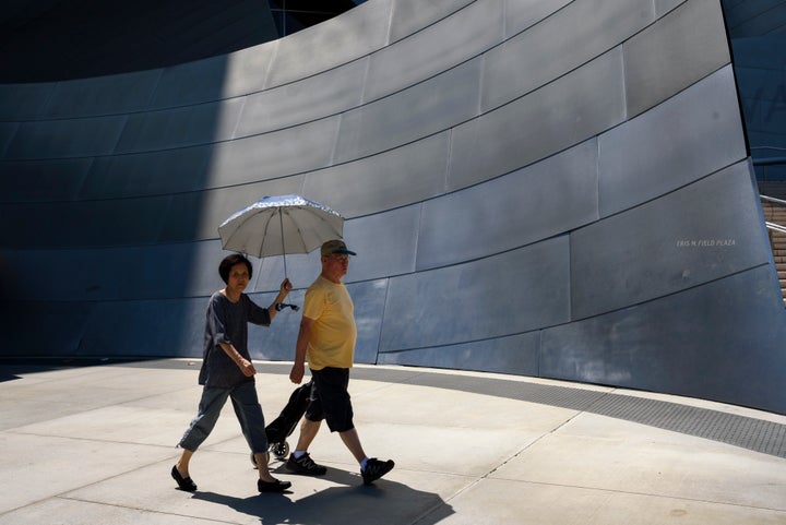 Pedestrians outside the Walt Disney Concert Hall in Los Angeles on Aug. 7 shield themselves from the sun as the temperature hits nearly 100 degrees. A new climate assessment says the average temperature in California will increase by 8.8 degrees by 2100.