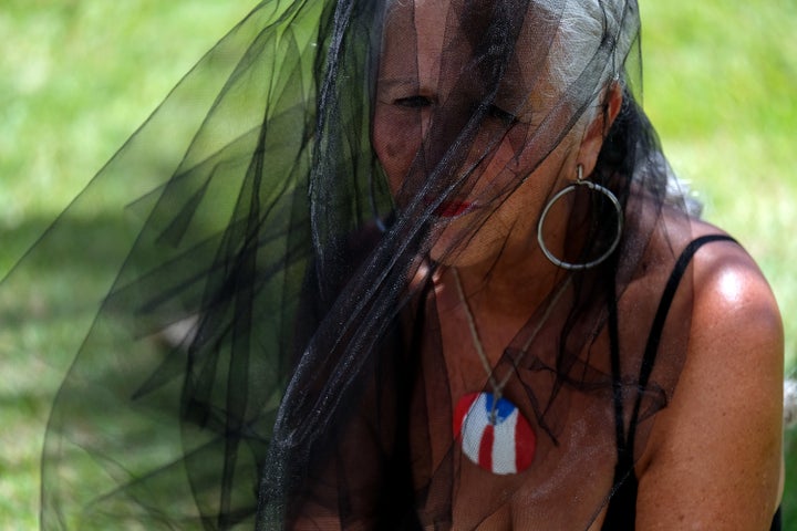 Aida Cruz Alicea, 68, prays in front of hundreds of shoes that were displayed in memory of those killed by Hurricane Maria, in front of the Capitol in San Juan, Puerto Rico, June 1.