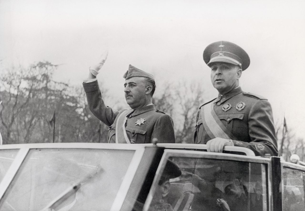 Franco (left) waves to the crowd as rides in a car with Minister of the Army Jose Varela during a parade for the second anniversary of their Civil War victory in Madrid, April 1941.