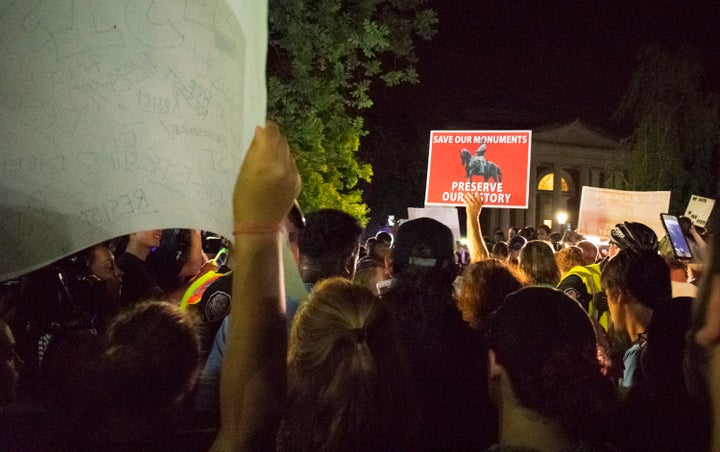 People opposed to a Confederate statue gather around as police escort a group of pro-statue demonstrators through barricades