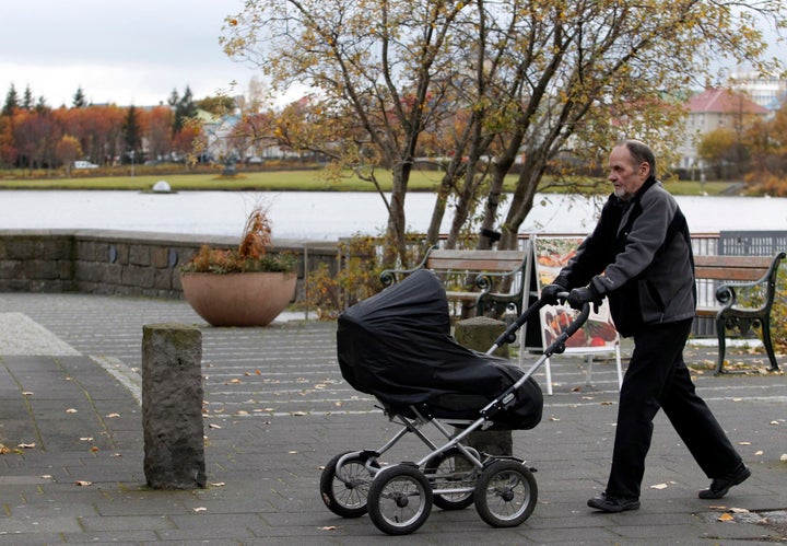 A man pushes a baby pram in a park in Reykjavik.