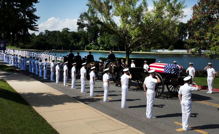 The horse-drawn caisson carrying the casket moves through the grounds of the U.S. Naval Academy.