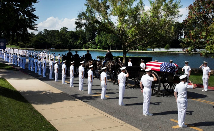The horse-drawn caisson carrying the casket moves through the grounds of the U.S. Naval Academy.