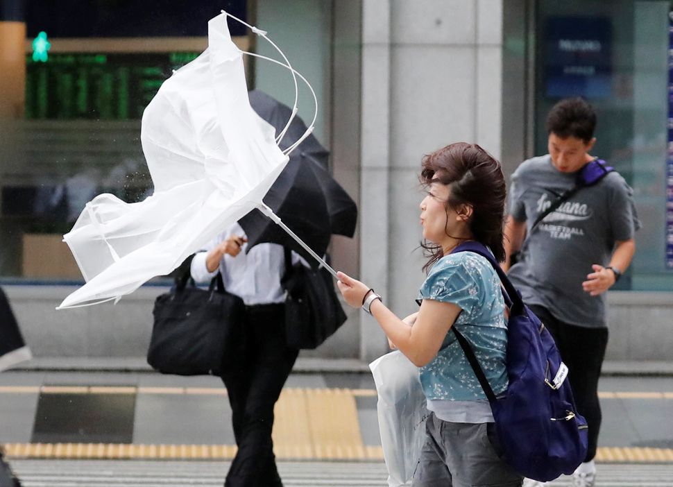 A woman using an umbrella struggles against strong wind and rain caused by Typhoon Jebi, in Tokyo.