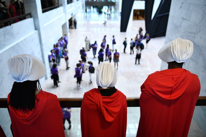 Women dressed as handmaids stood to protest Brett Kavanaugh.