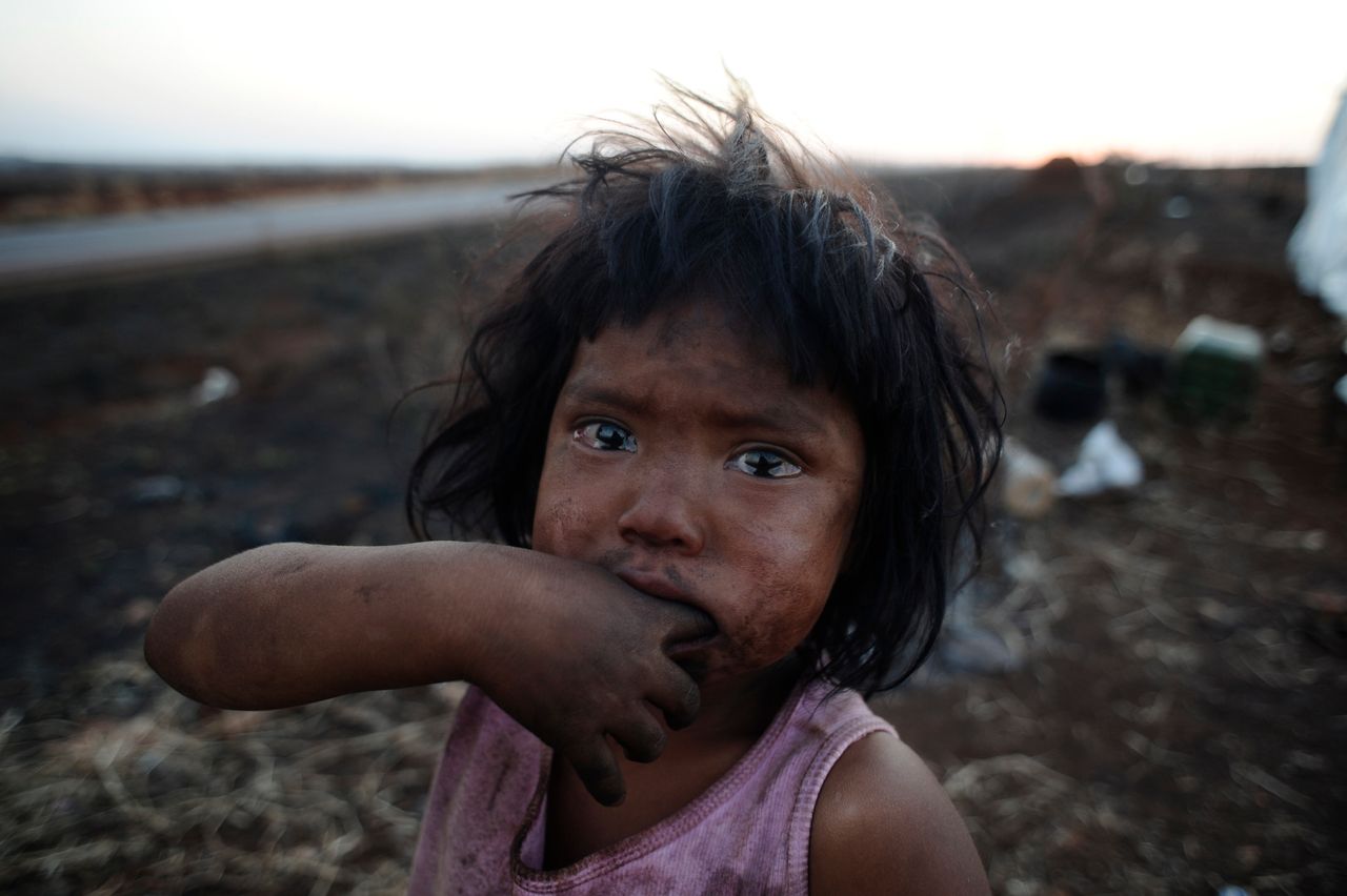 A Guarani Kaiowa Indian girl, Sandriely, in front of her hut near Dourados in Mato Grosso do Sul state, Brazil, which has been destroyed by a fire set by an unknown arsonist. Her tribe is immersed in a bloody conflict with farmers over possession of their ancestral land.