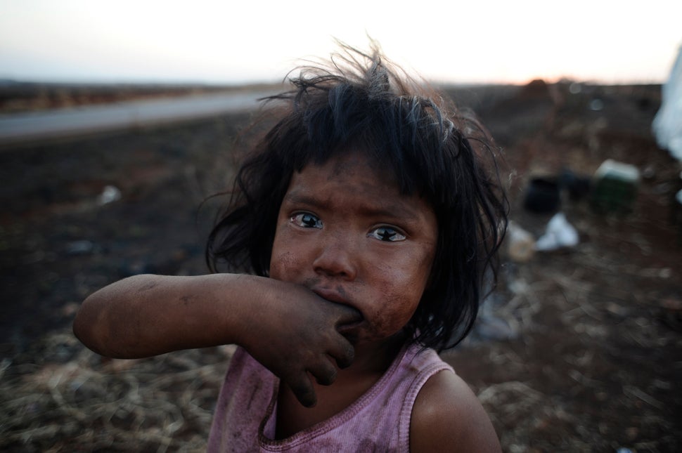 A Guarani Kaiowa Indian girl, Sandriely, in front of her hut near Dourados in Mato Grosso do Sul state, Brazil, which has been destroyed by a fire set by an unknown arsonist. Her tribe is immersed in a bloody conflict with farmers over possession of their ancestral land.