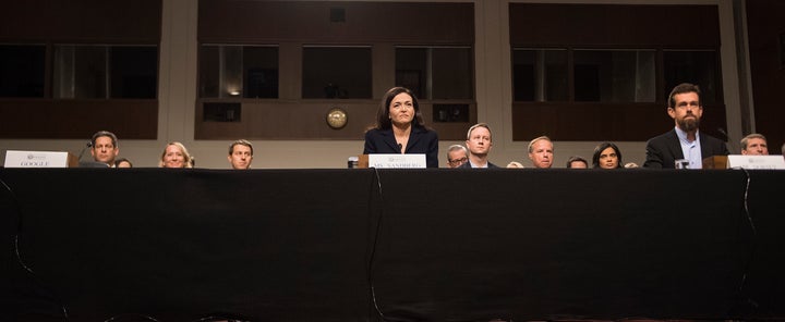 An empty chair on the left marks the absence of anyone from Google as Facebook COO Sheryl Sandberg and Twitter CEO Jack
