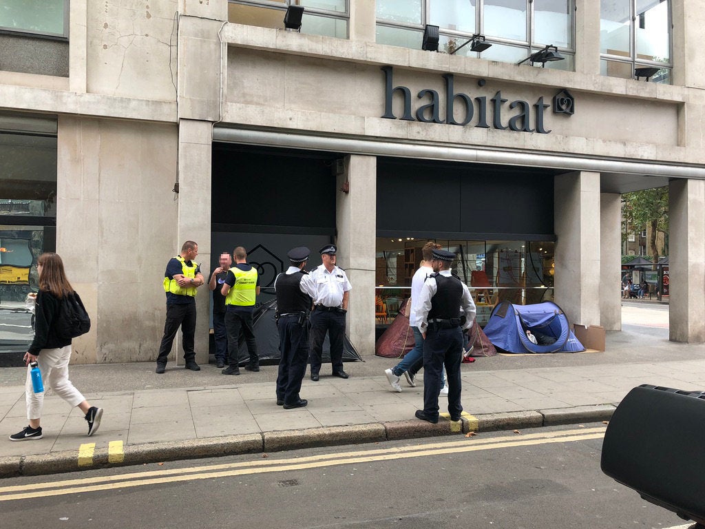 Police and outreach workers carrying out a patrol speak to the men in tents outside Habitat