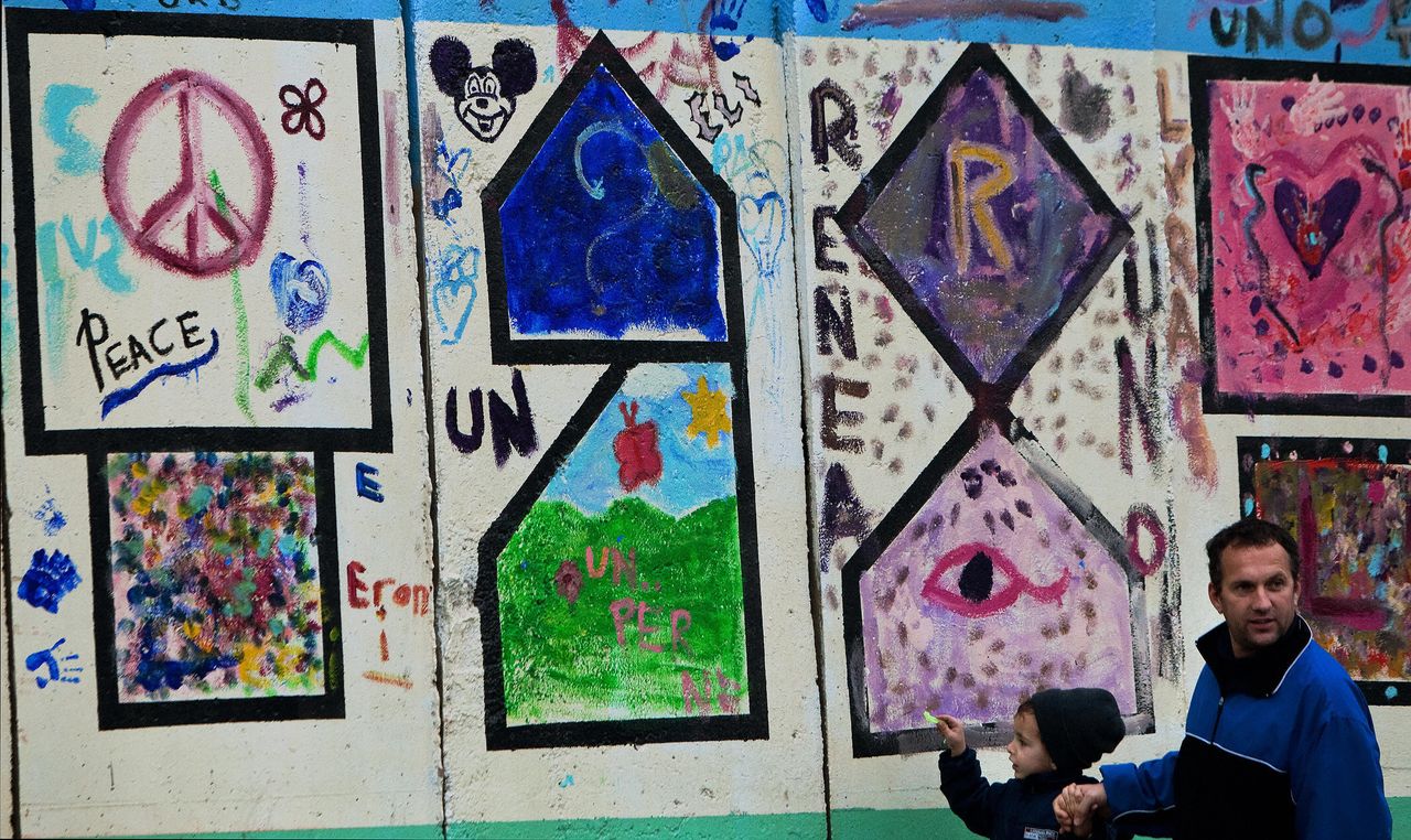 Αλβανός Κοσοβάρος περπατά πλάι σε τοίχο με συνθήματα και ζωγραφιές για την Ειρήνη στην Πρίστινα