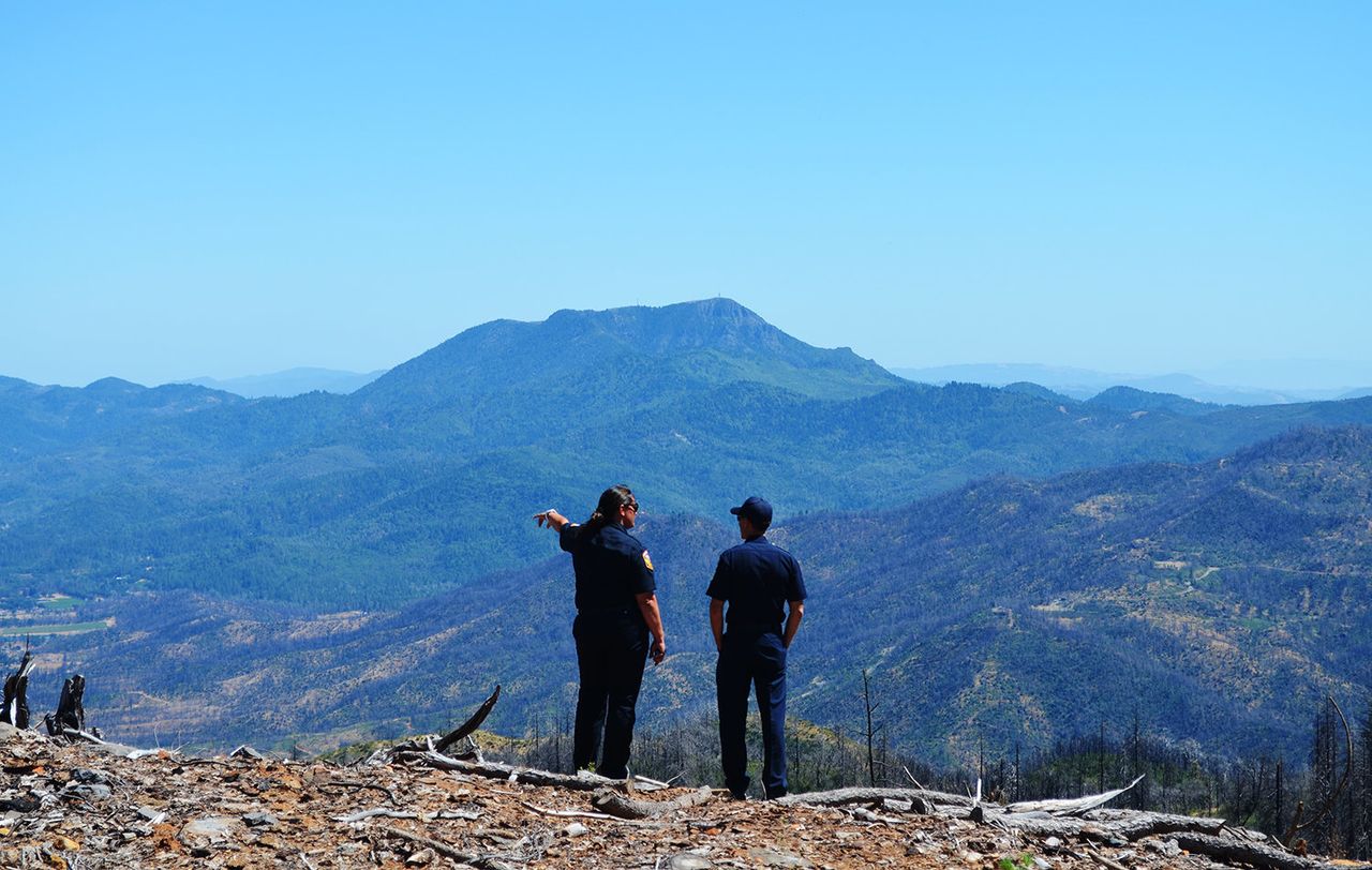 Emily Smith and Chris Anthony, both of Cal Fire, overlook a fire-scarred mountainside in Lake County, California. 