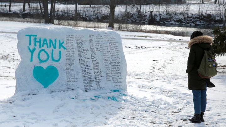 A Michigan State University student stops to look at "The Rock" painted with the names of survivors of Larry Nassar in East Lansing, Michigan, on Feb. 11, 2018. 