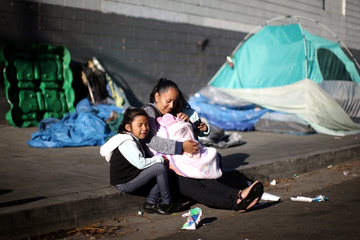 Samantha Cadena sits with her daughters as they wait in line with other needy families to receive free back-to-school supplies from the Fred Jordan Mission in Los Angeles.