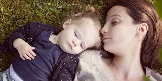 Mother and baby girl napping on grass