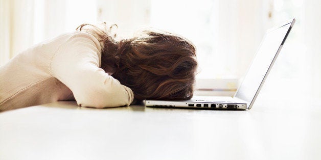 Teenage girl (16-17) lying on table with laptop, rear view