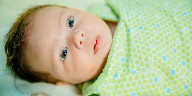 Caucasian baby boy swaddled in blanket