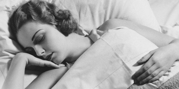 Young woman asleep in bed, (B&W), close-up