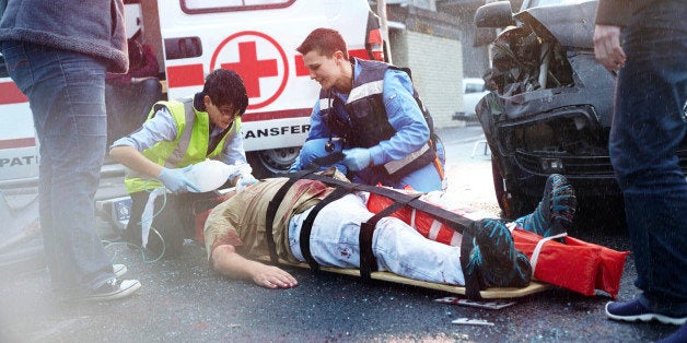 Rescue workers tending to car accident victim in road