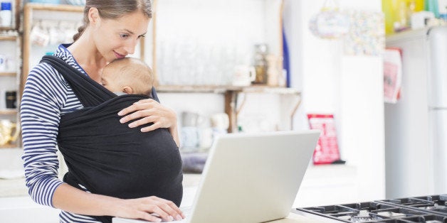 Mother with baby boy using laptop in kitchen