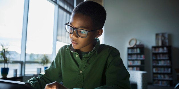 Elementary student using digital tablet in dark library