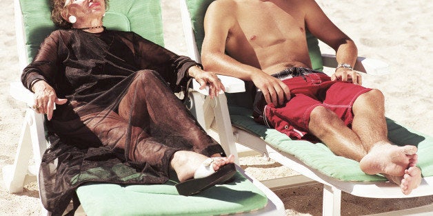 Mature woman and young man relaxing on sun loungers