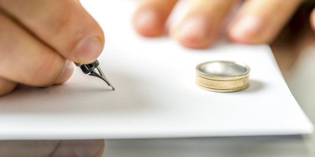 Closeup of male hand signing divorce papers.