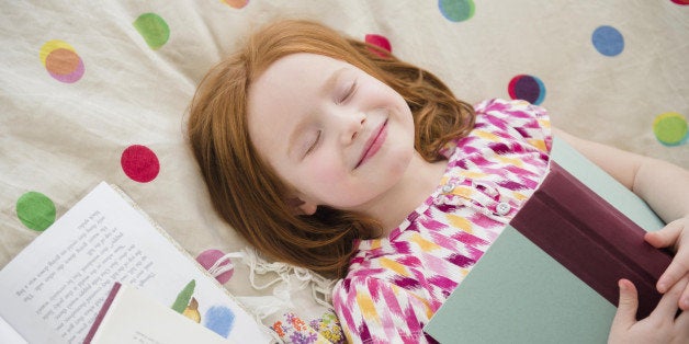 Caucasian girl reading books on bed