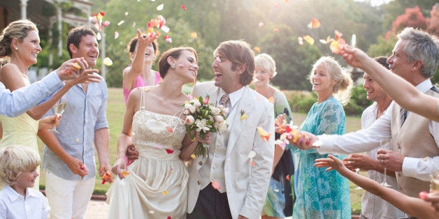 Guests throwing rose petals on bride and groom