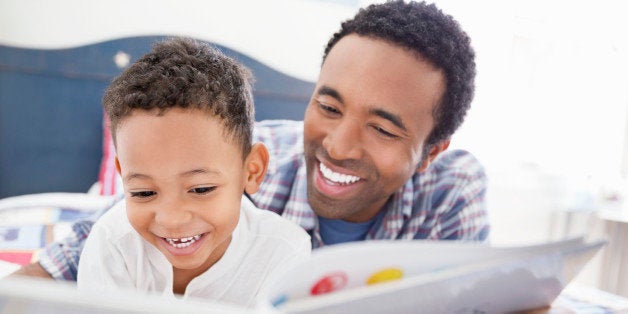 Happy father and son reading book together in bed