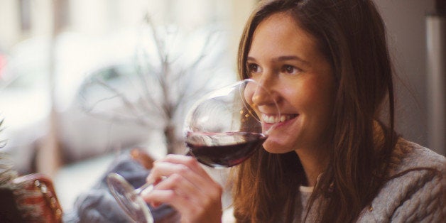 Beautiful happy lady drinking glass of red wine.