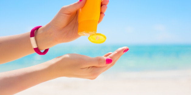 Woman using sunscreen cream in yellow bottle.