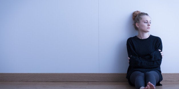 Lonely thoughtful girl sitting on the floor