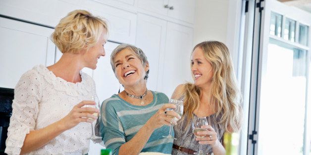 Cheerful two generation women with wine glasses in kitchen