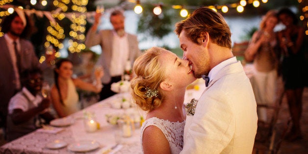 Young couple kissing during wedding reception in domestic garden