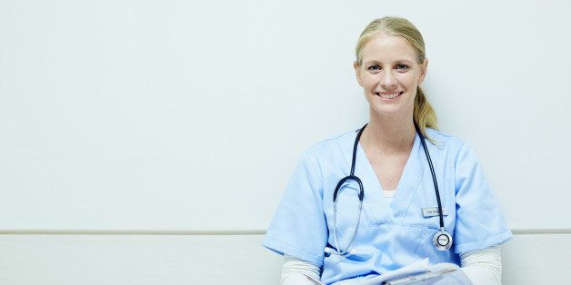 Portrait of happy female nurse with clipboard sitting in hospital