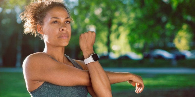 Woman wearing smart watch stretching at park