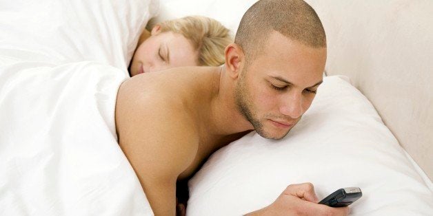 Young man text messaging with young woman sleeping