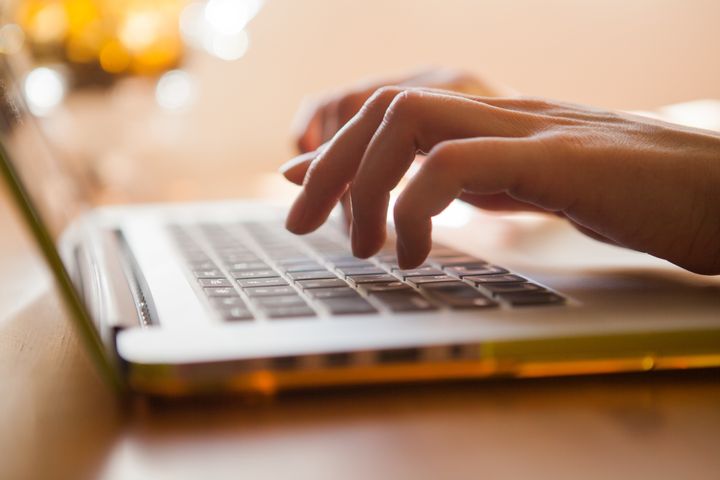 A close-up shot of a woman's hands as she types on a laptop keyboard.