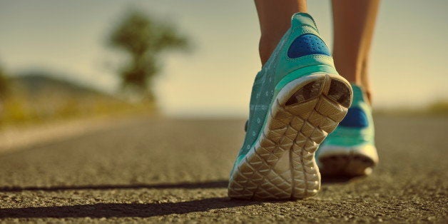 Closeup of athlete female feet in running shoes jogging on the road early in the morning. Healthy lifestyle.