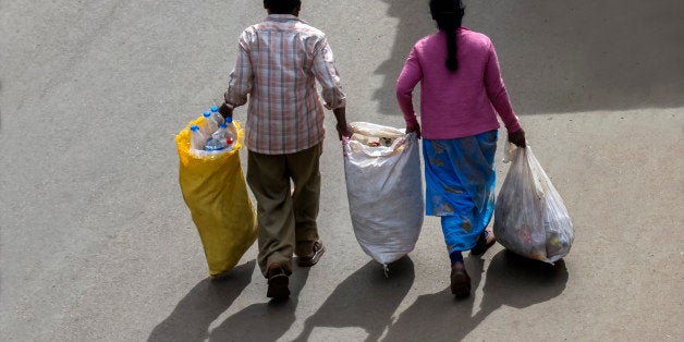 Two road cleaning workers are carrying a large quantity of wastes in bags to disposing dump yard.