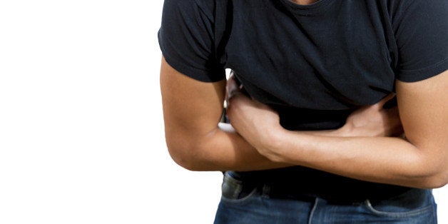 Closeup portrait, young business man, unhealthy, unwell corporate worker, doubling over in gastrointestinal stomach pain, isolated white background. Human emotions. Acute abdomen