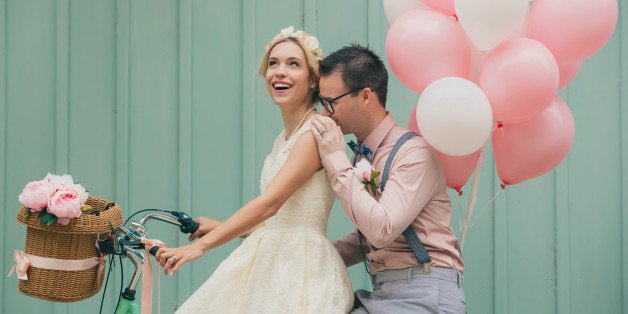 Happy couple smiling on a wedding day, with retro bike and vintage outfit.