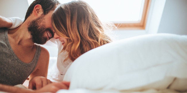 Lovely couple in pyjamas spending Valentine's day in their bed, and sharing their love and affection