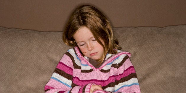 sad little girl sitting by herself on couch