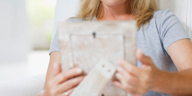 Frowning woman looking at picture frame