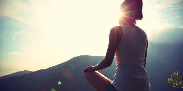 young yoga woman at sunrise mountain peak